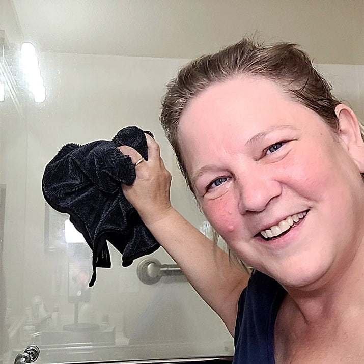 Person holding a black towel in front of a mirror
