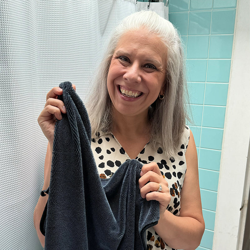 Woman holding a towel in a bathroom with light blue tiles.