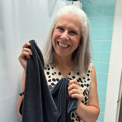 Woman holding a towel in a bathroom with light blue tiles.